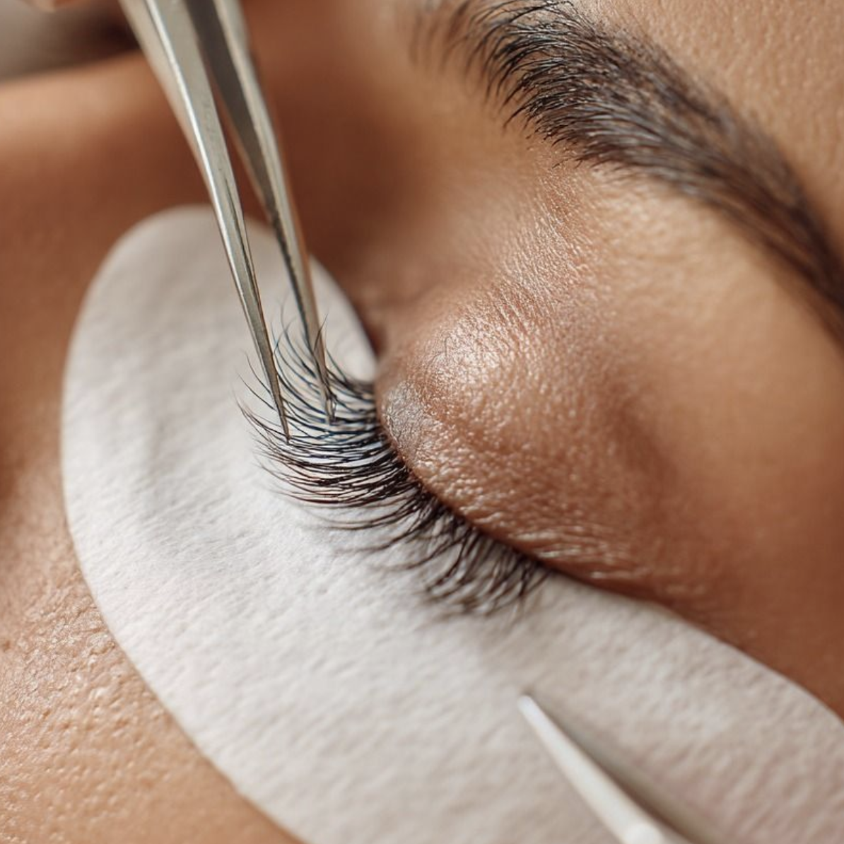 Close-up of eyelash extension application with tweezers