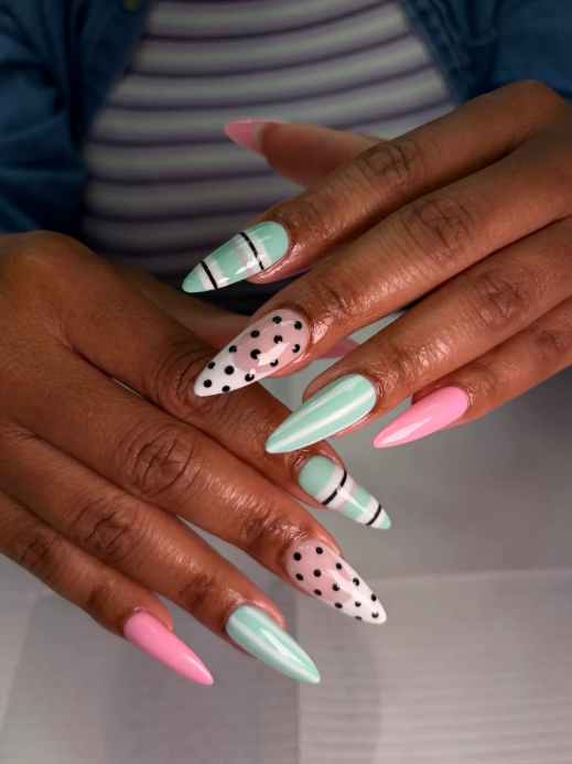Mint and pink stiletto nails with black polka dots and striped accent nails