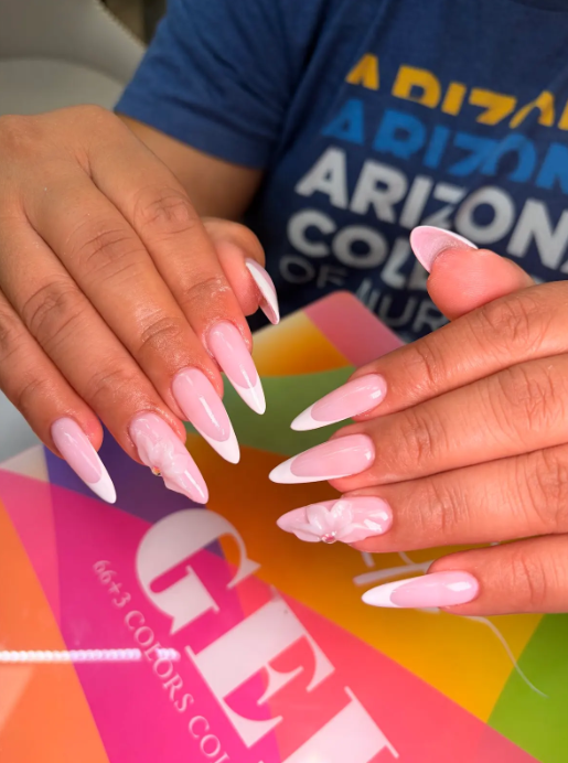 Soft pink stiletto nails with white French tips and a 3D flower accent